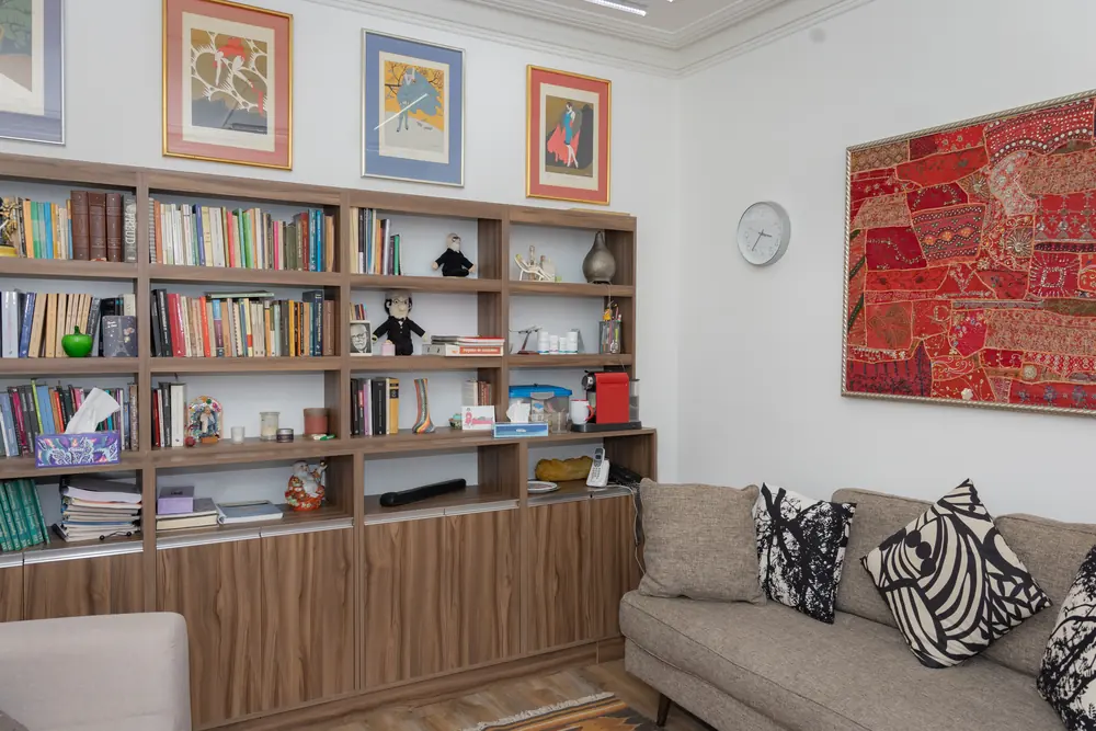 Sala de consulta con sofá, librero y tapiz rojo en Kairós Centro